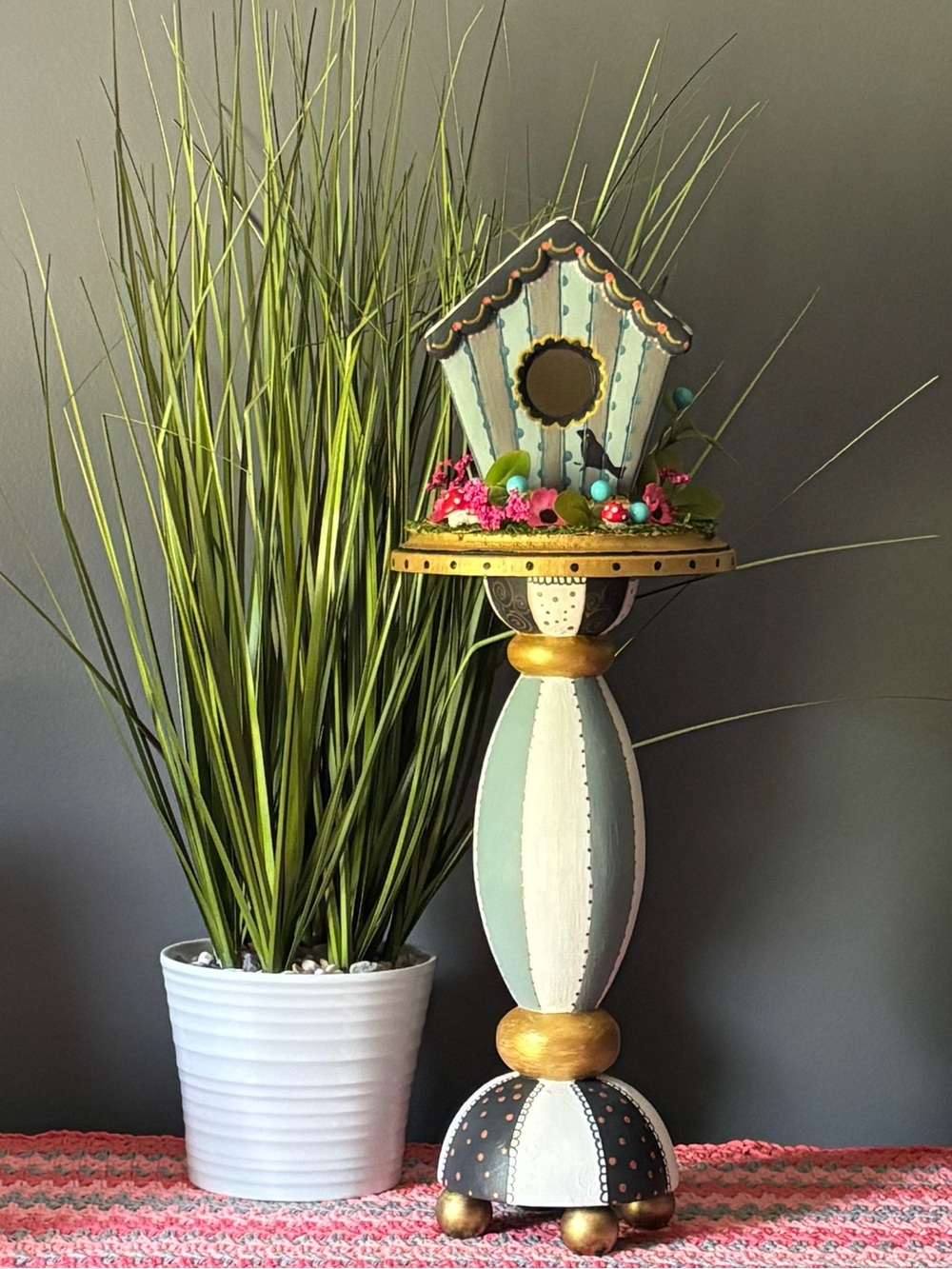 Whimsical hand painted birdhouse on pedestal.